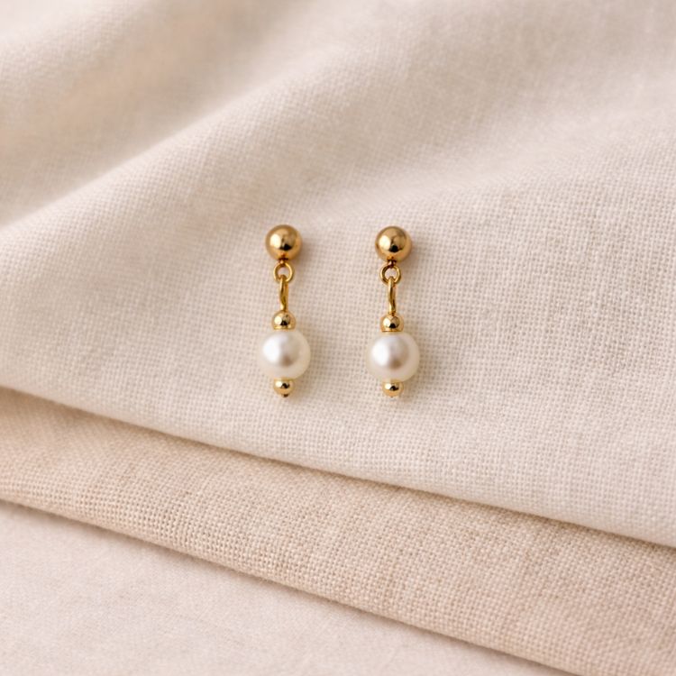 Aretes de perla blanca pequeños en composición minimalista