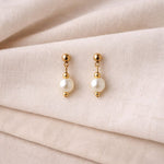 Aretes de perla blanca en flat lay elegante