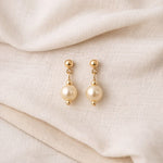 Aretes de perla crema en flat lay suave