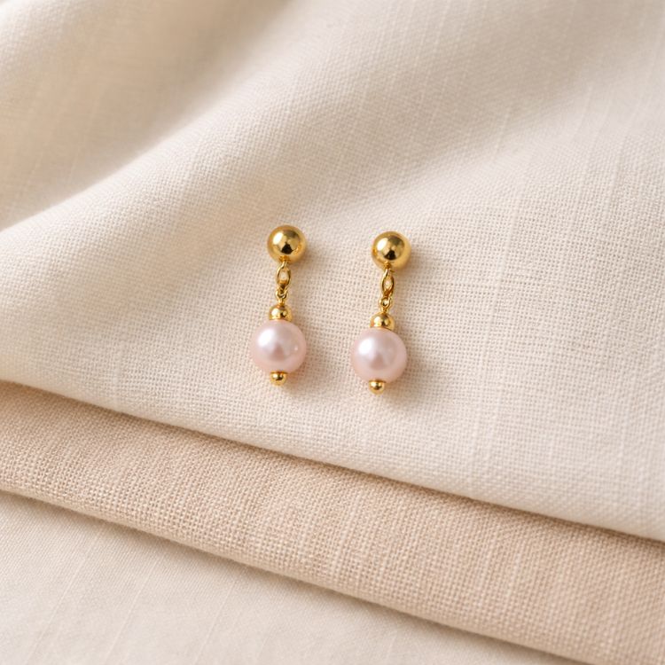 Aretes de perla rosa pastel en composición estética