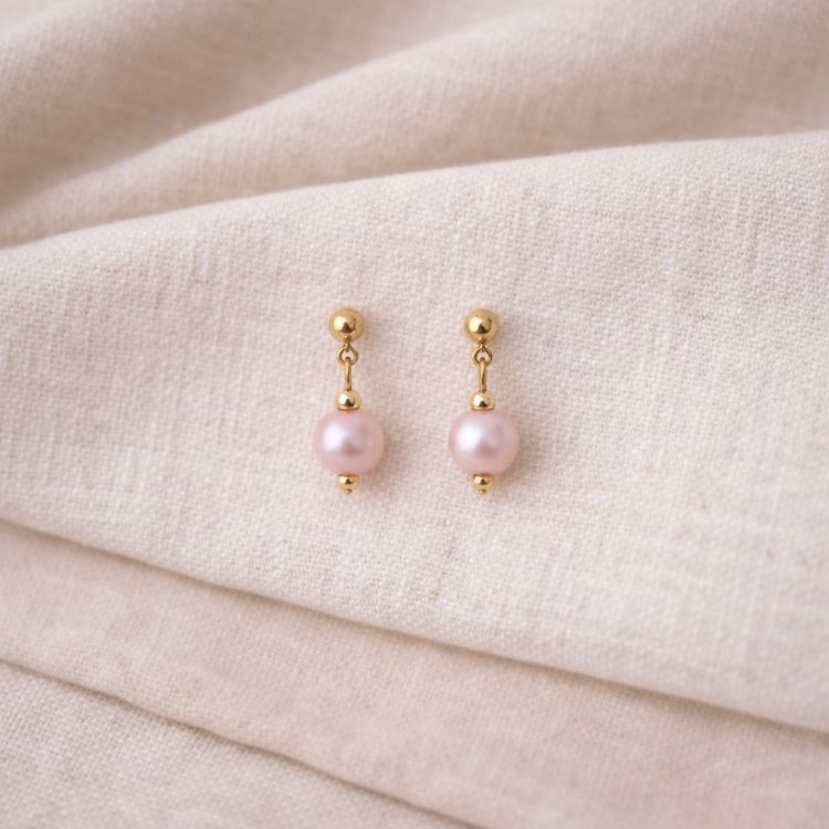 Aretes de perla rosa pastel en flat lay femenino