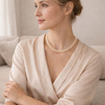 Mujer sentada con collar doble de perla crema ligero