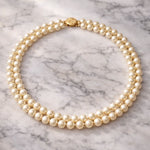 Collar doble de perla crema sobre mármol elegante