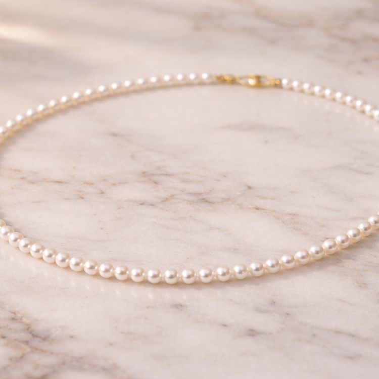 Collar de perla blanca fino sobre mármol