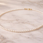 Collar de perla blanca fino sobre mármol