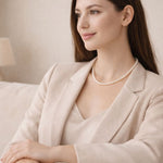 Mujer sentada con collar de perla blanca discreto