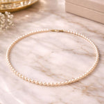 Collar de perla crema pequeño sobre mármol