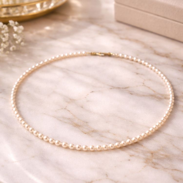 Collar de perla crema pequeño sobre mármol