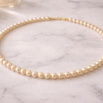 Collar de perla crema sobre superficie de mármol