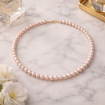 Collar de perla rosa pastel pequeño sobre mármol
