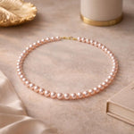 Collar de perla rosa pastel en flat lay femenino