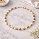 Collar de perlas café crema sobre mármol