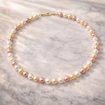 Collar de perlas tricolor sobre superficie de mármol