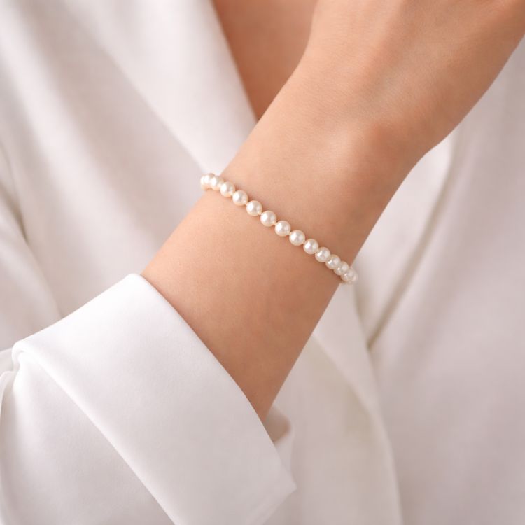 Mujer usando pulsera de perla blanca delicada