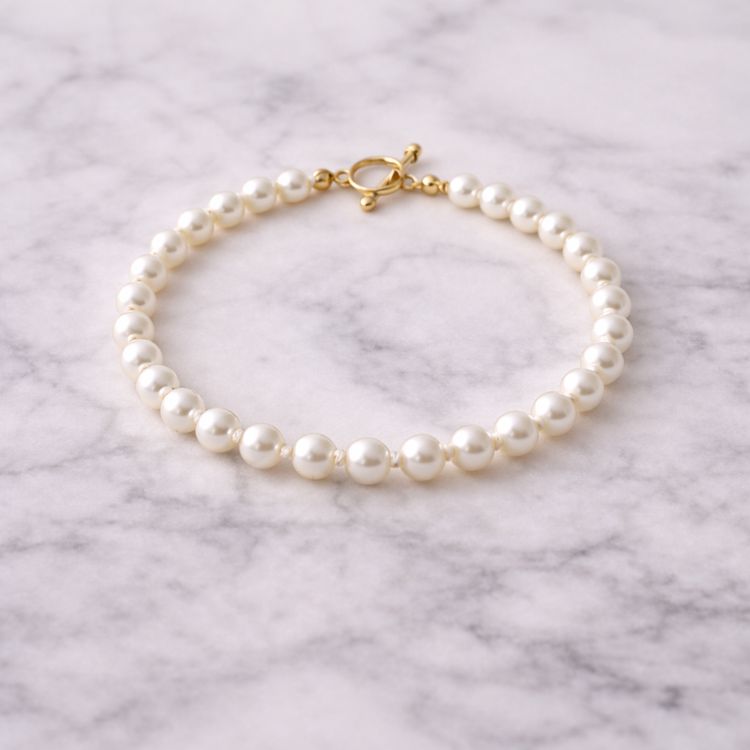 Pulsera de perla blanca fina sobre mármol
