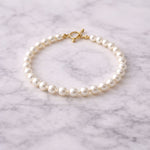 Pulsera de perla blanca fina sobre mármol