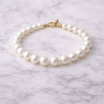 Pulsera de perla blanca sobre superficie de mármol