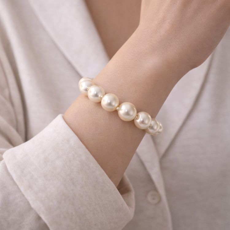 Mujer usando pulsera de perla crema protagonista