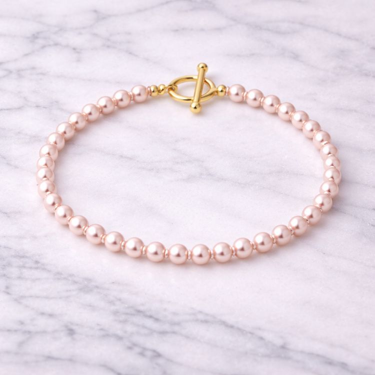 Pulsera de perla rosa pastel pequeña sobre mármol