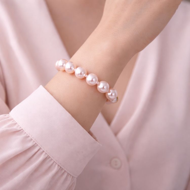 Mujer usando pulsera de perla rosa pastel elegante