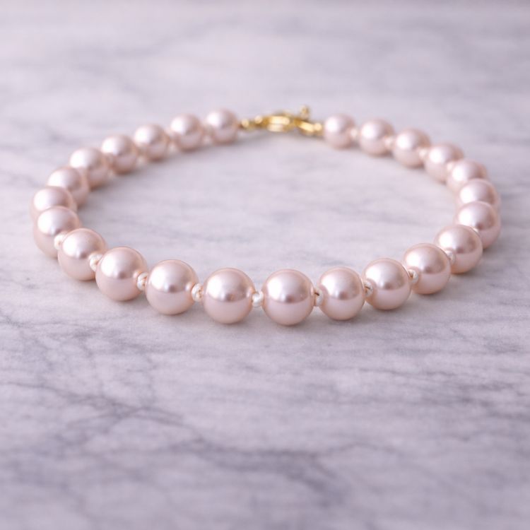 Pulsera de perla rosa pastel sobre superficie de mármol