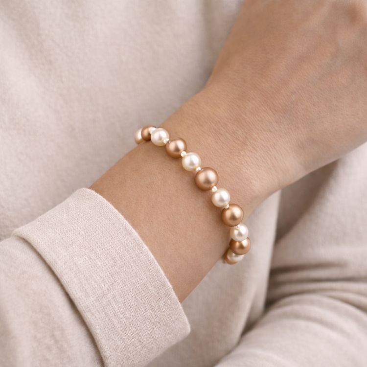 Mujer usando pulsera de perlas en tonos cálidos