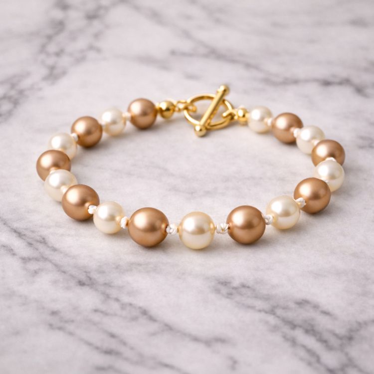 Pulsera de perlas café crema sobre mármol