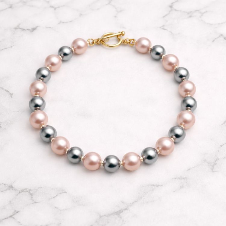 Pulsera de perlas rosa gris sobre mármol