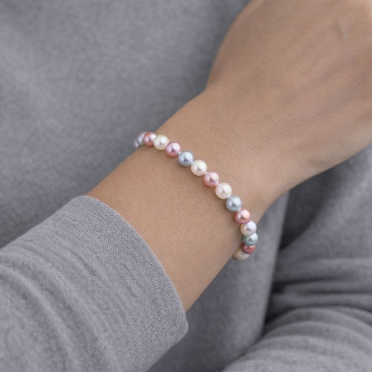 Mujer usando pulsera de perlas rosa gris y crema