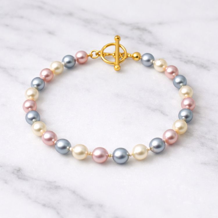 Pulsera de perlas tricolor fina sobre mármol