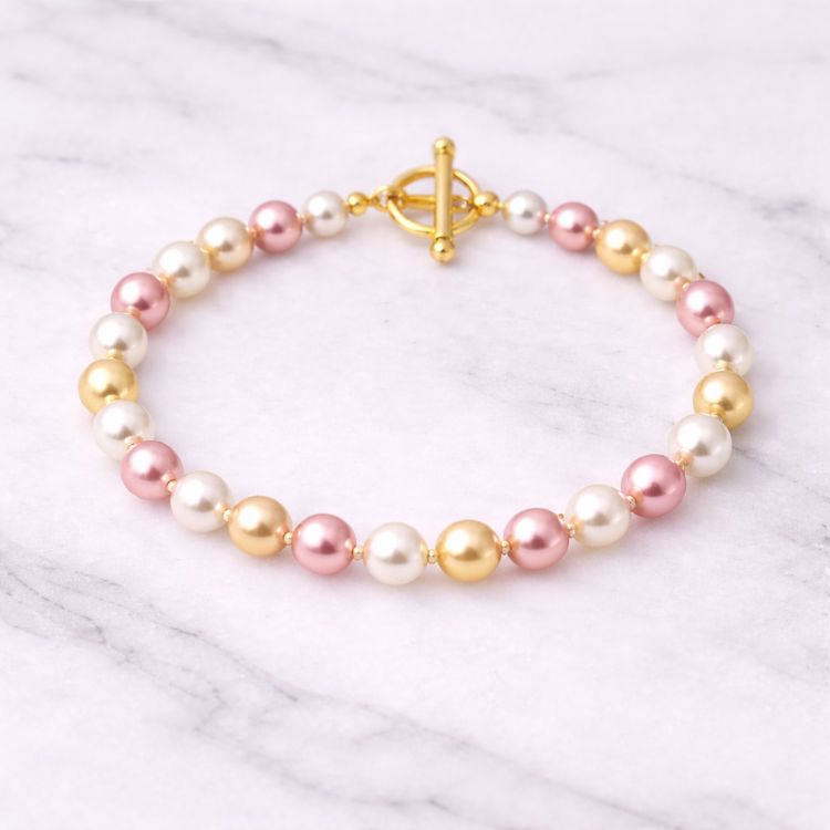 Pulsera de perlas tricolor sobre superficie de mármol